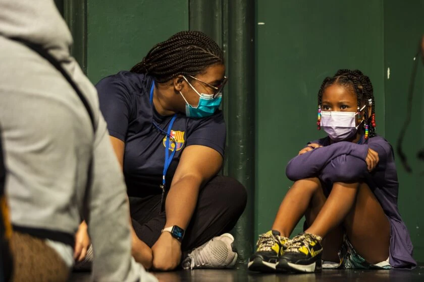 Councilor Kierra Towns, 25, who lost her mother as a child, chats with Mia as other children play during Hearts to Art summer camp on July 11. 