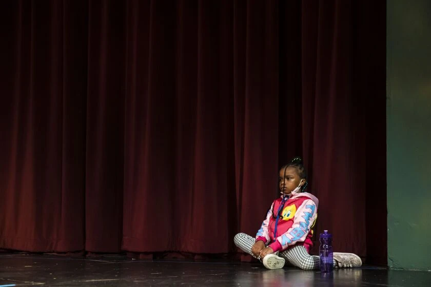 Lizzette, 6, sits nearby as other children chat and play during Hearts to Art, a summer camp for children whose parents have passed away. 