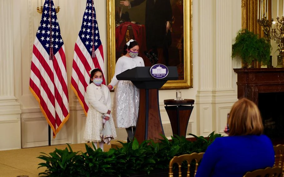 Gabby Rodriguez, 9, touches the shoulder of her six-year-old sister Ava as she talks about their experiences as the children of an injured veteran at an event honoring child caregivers in the East Room of the White House on Wednesday, November 10, 2021. 