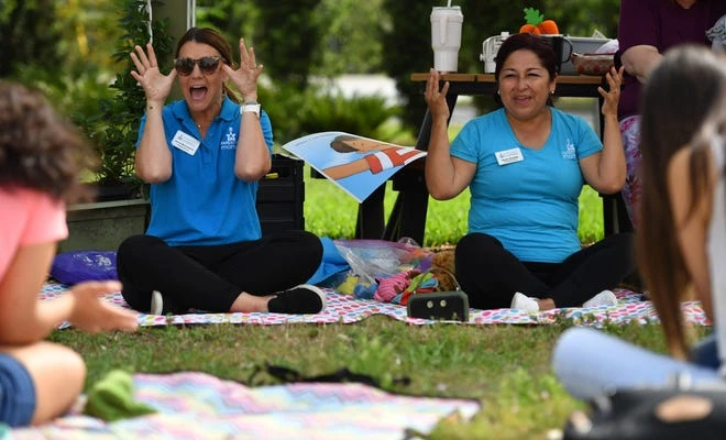 Parenting educators with Parenting Matters, Jenny McConachy, left, and Rocio Gormley, right, lead the group in a song during the Musical Motion program.