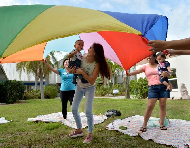 Diana Ranfla carries her son, Osleih Mendez, 13 months, under a colorful canopy held aloft by other mothers from the Musical Motion programme.
