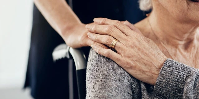 Cropped shot of caregiver comforting senior woman
