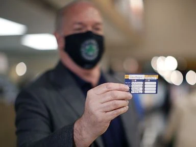 Prime Minister John Horgan shows his vaccination card after receiving a dose of the AstraZeneca COVID-19 vaccine at the pharmacy in April.
